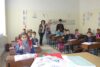 Kinder,Lehrerin und Priester freuen sich gemeinsam, dass die eist zermombte Schule wieder in Betrieb ist (csi)